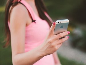 woman in pink using iphone