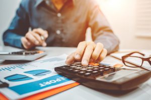 A person in a dress-shirt uses a calculator to determine a monthly budget.