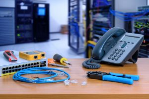 Cables, hardware, and tools sit on a desk next to a phone.