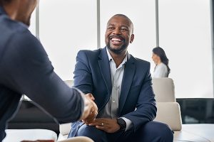 A smiling man in a business suit shakes the hand of a business partner.