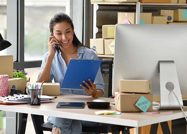 A happy businessperson smiles at a clipboard while talking on the phone.