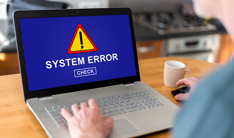 A person is typing on a laptop with a blue screen and a system error warning.