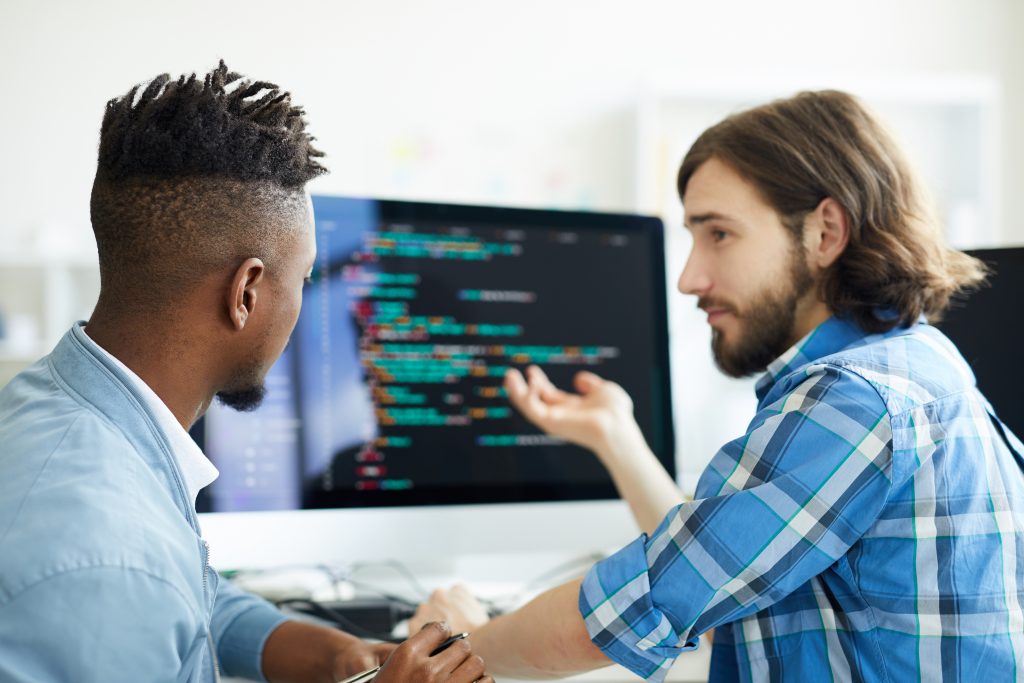 A man is explaining something on a computer to another man.