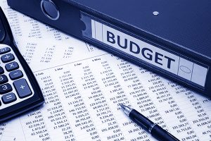 A printed budget on a table with a calculator, pen, and budget binder.