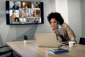 A woman speaks on a conference call on a headset and laptop.