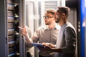 Two cybersecurity professionals manage a network server together.