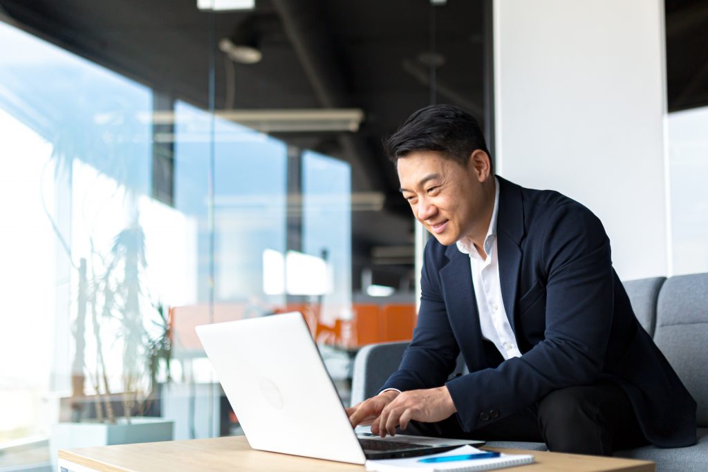 A man smiling and working on his laptop.