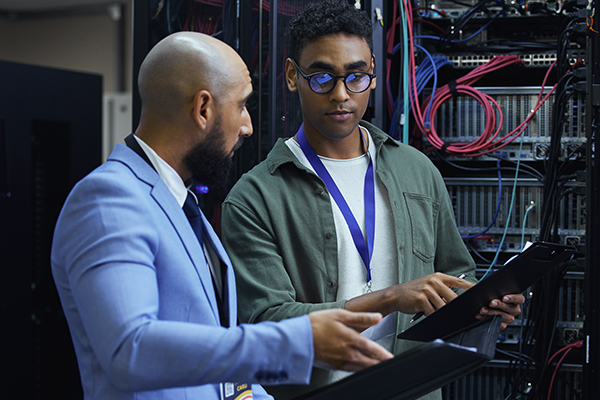 Two men review an IT diagnostic report in a server room.