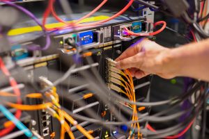 A hand plugging in a cable in a server box